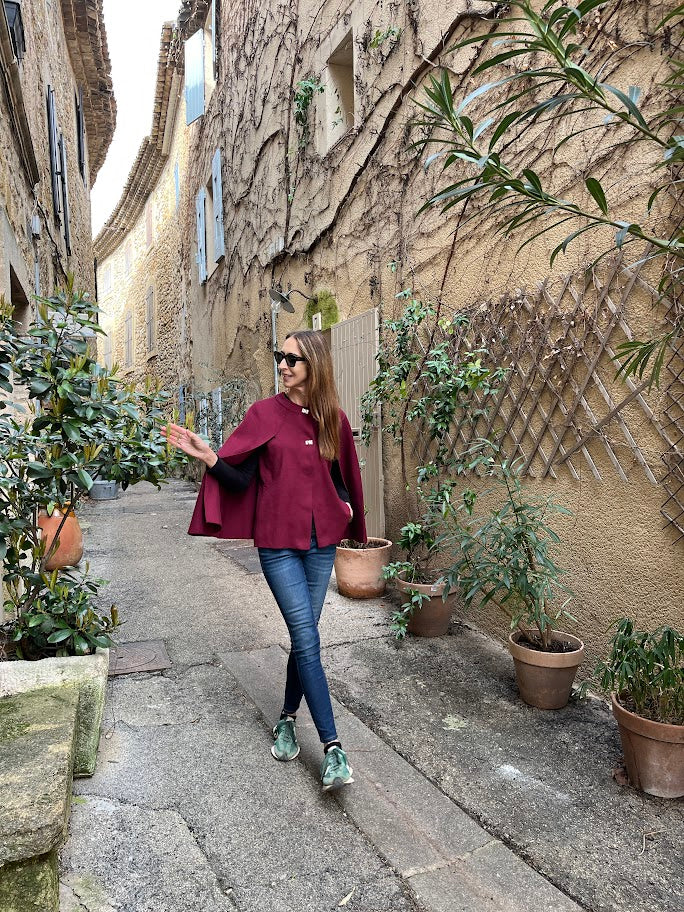 Kntted cape in Bordeaux with metal stud closures on the front.